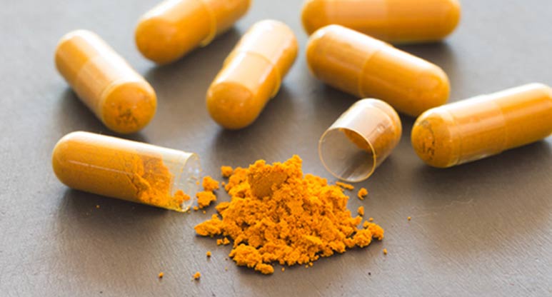 Several supplement capsules full of orange powder
